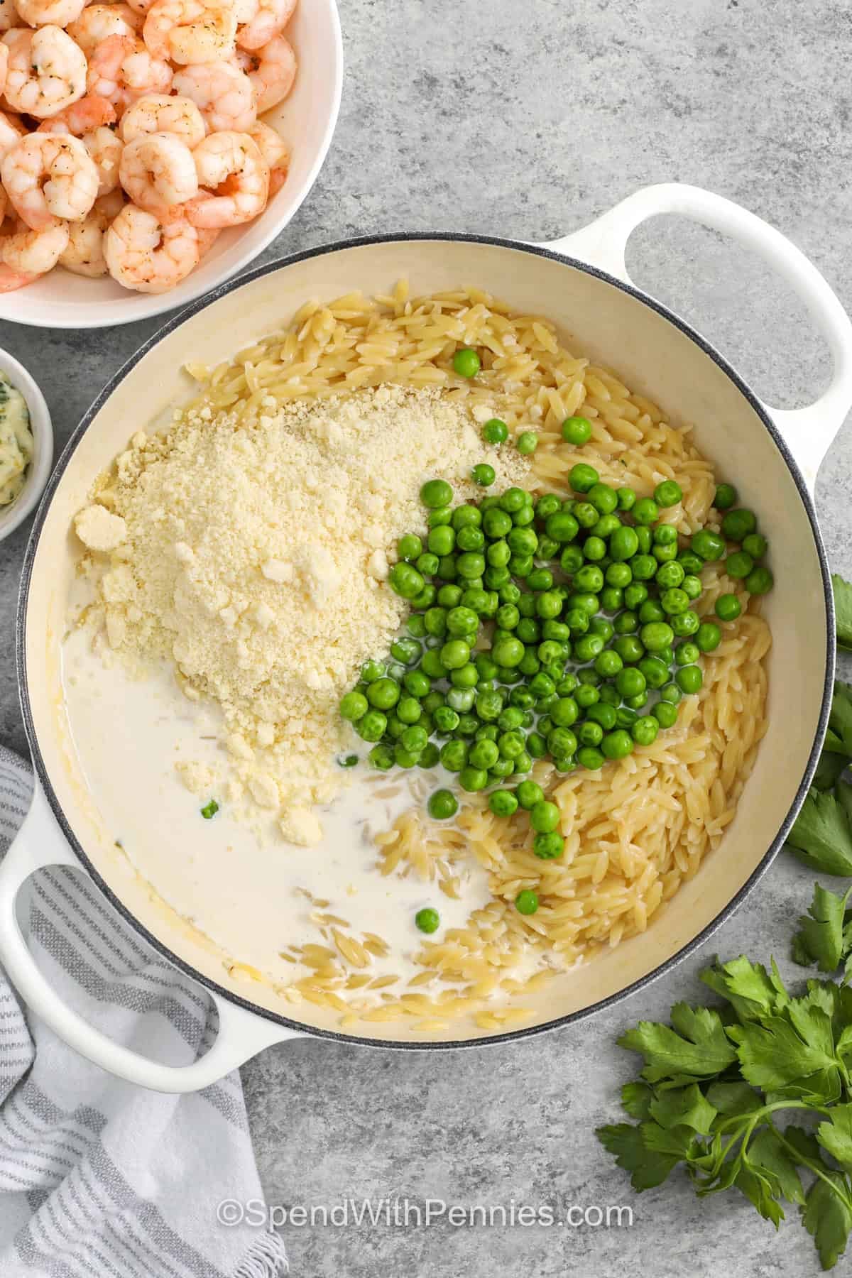 adding whipping cream, parmesan and peas to pot to make Garlic Butter Shrimp Orzo