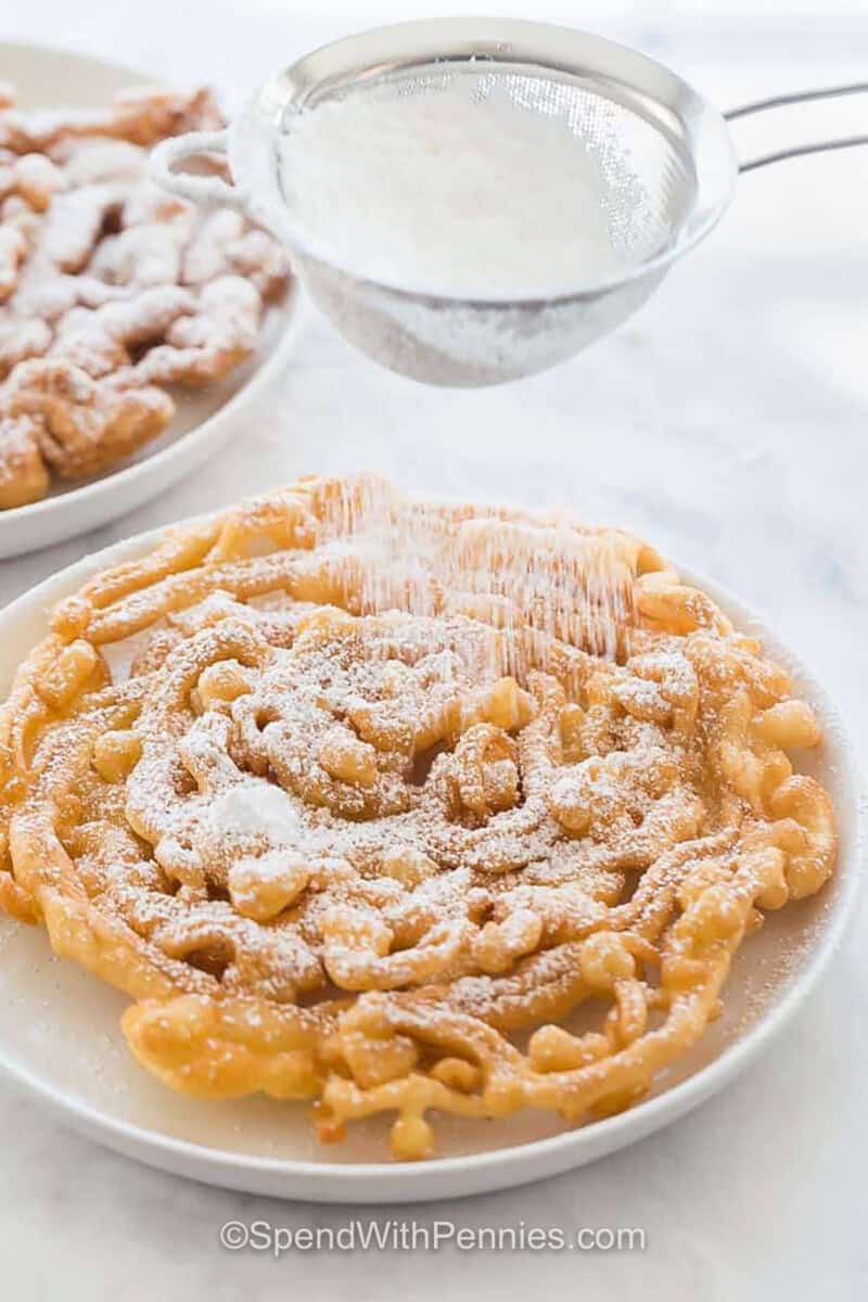 adding powdered sugar to Homemade Funnel Cake