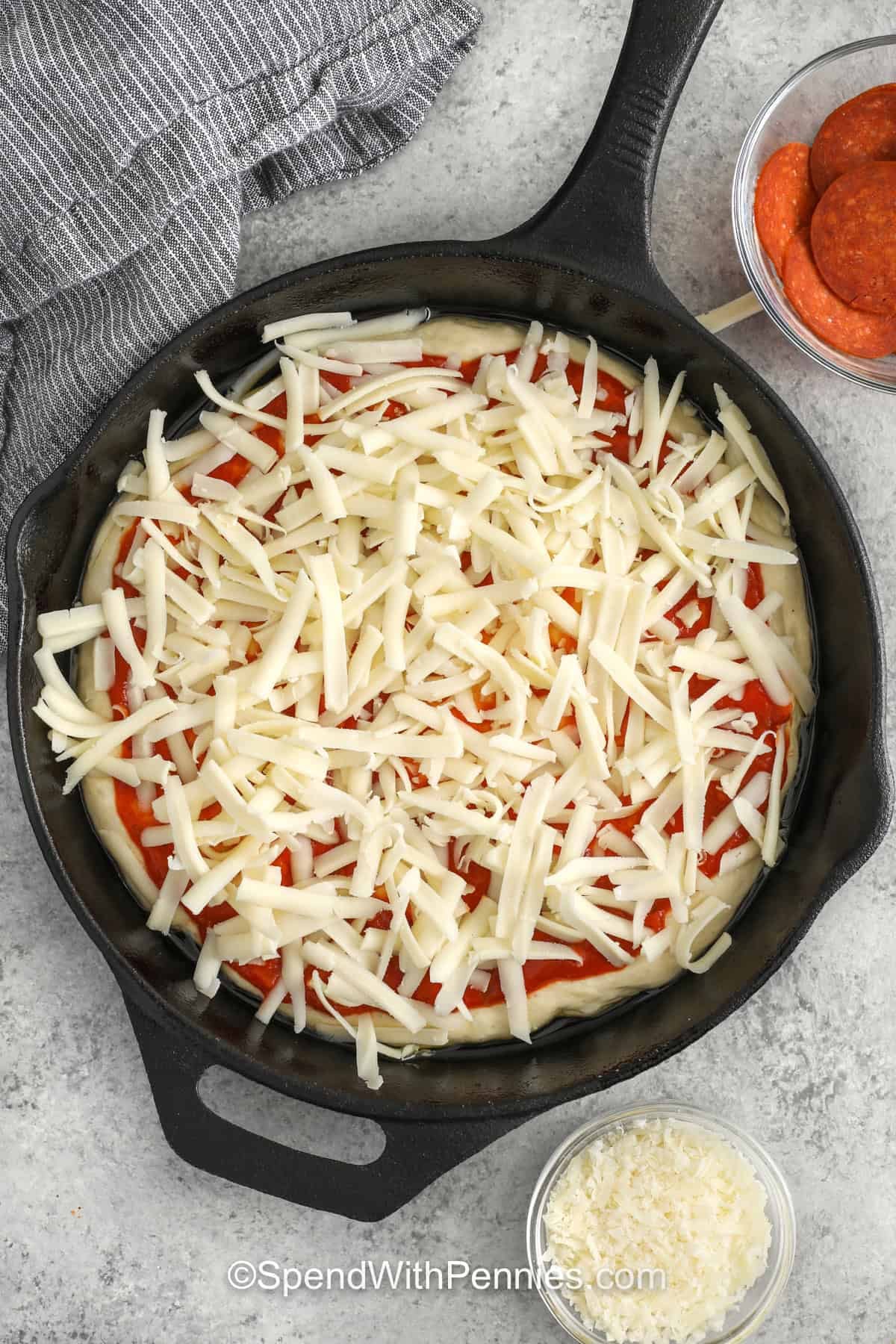 This pepperoni pan pizza is all about easy ingredients and big payoff. The crust bakes up golden and crisp from the olive oil in the pan, while the mozzarella melts into a bubbly layer under savory pepperoni and Parmesan. It is a dependable homemade recipe that works well for weeknights, movie nights, or anytime you want a simple cast iron skillet pizza that tastes satisfying and comforting. #spendwithpennies adding cheese to pizza dough to make Homemade Pan Pizza