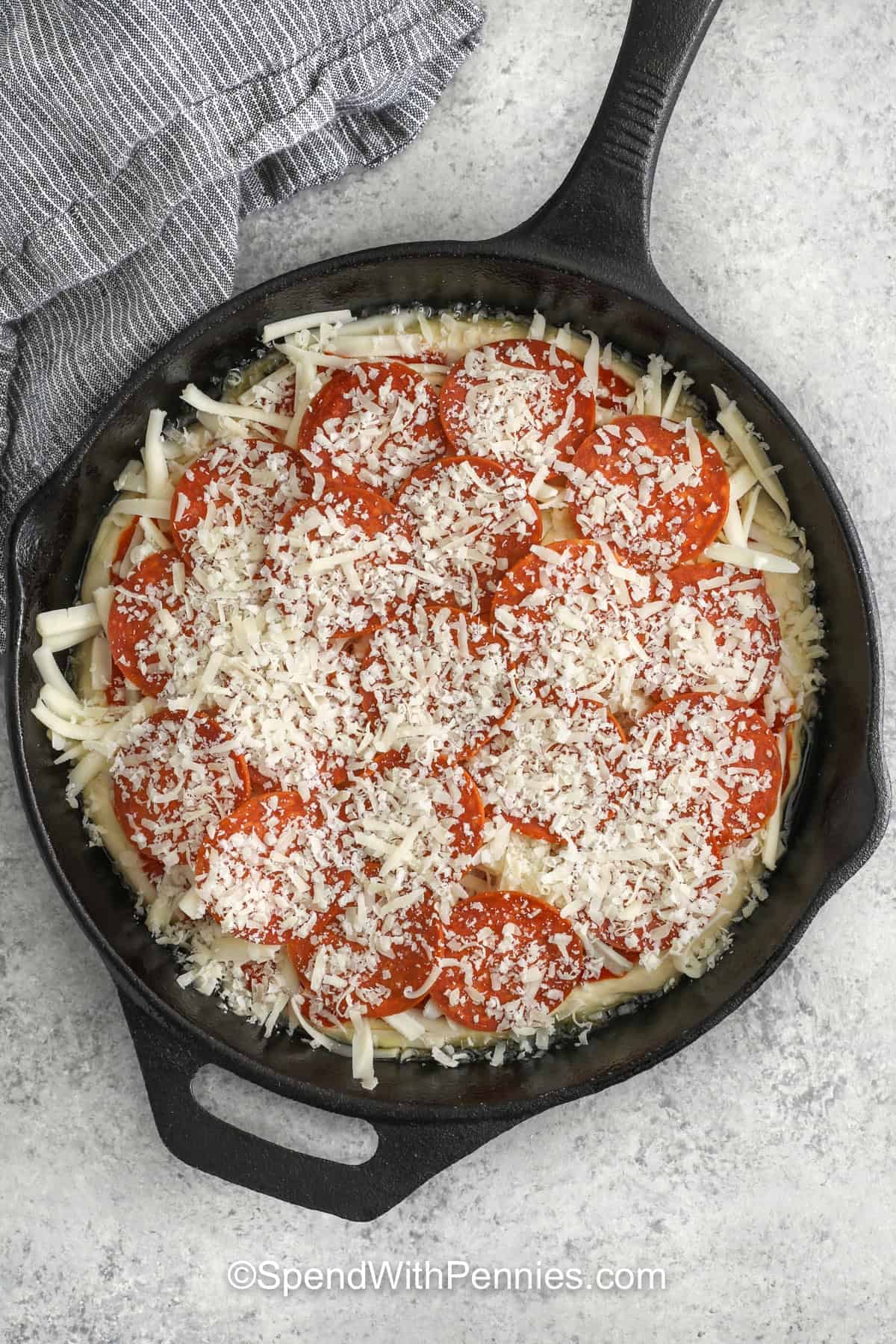 If you love skillet pizza, this pan pizza is a great one to save for easy dinners. A ready dough ball is pressed into an olive oil-coated cast iron skillet, then topped with sauce, mozzarella, pepperoni, and Parmesan before baking until bubbly. The result is a thick, crisp-edged pizza with classic flavor and a texture that feels just right for family pizza night or simple entertaining. #spendwithpennies adding pepperoni and parmesan to pizza dough to make Homemade Pan Pizza