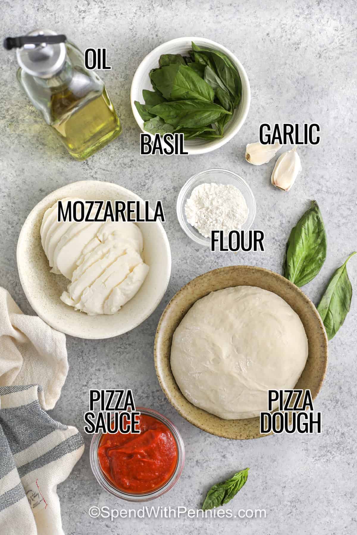 oil , basil , garlic , flour , mozzarella , pizza dough , pizza sauce with labels to make Margherita Pizza