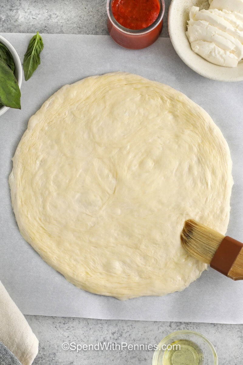 brushing oil over pizza dough to make Margherita Pizza