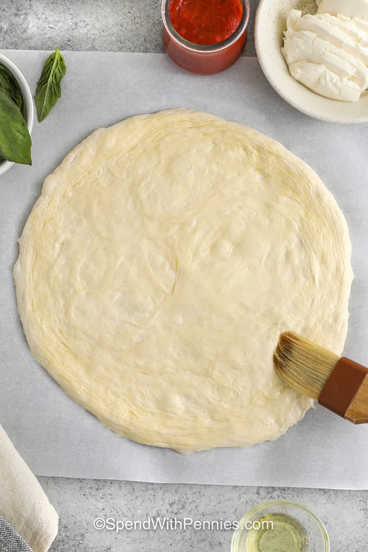 brushing oil over pizza dough to make Margherita Pizza