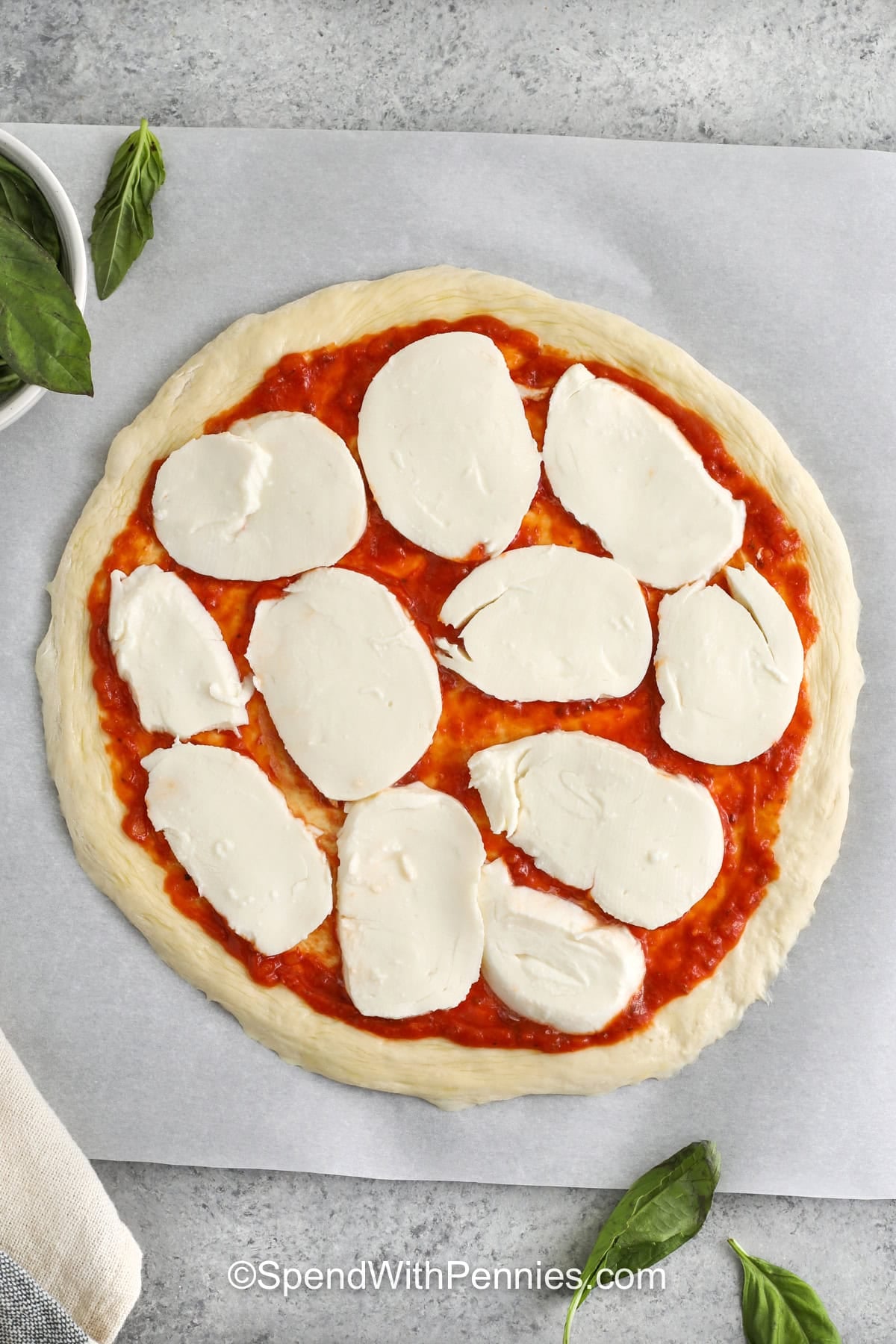 adding mozzarella slices to pizza to make Margherita Pizza