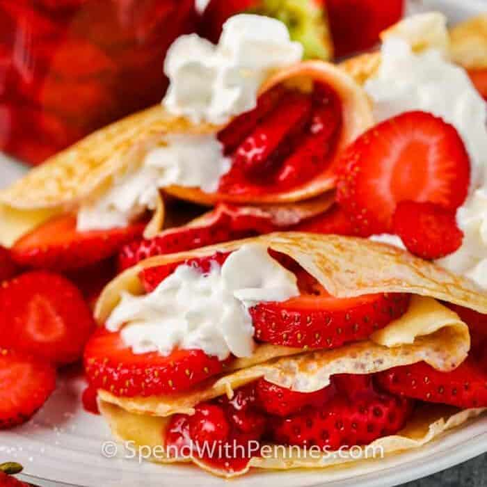 Strawberry Crepes on a plate with jar of strawberries in the background