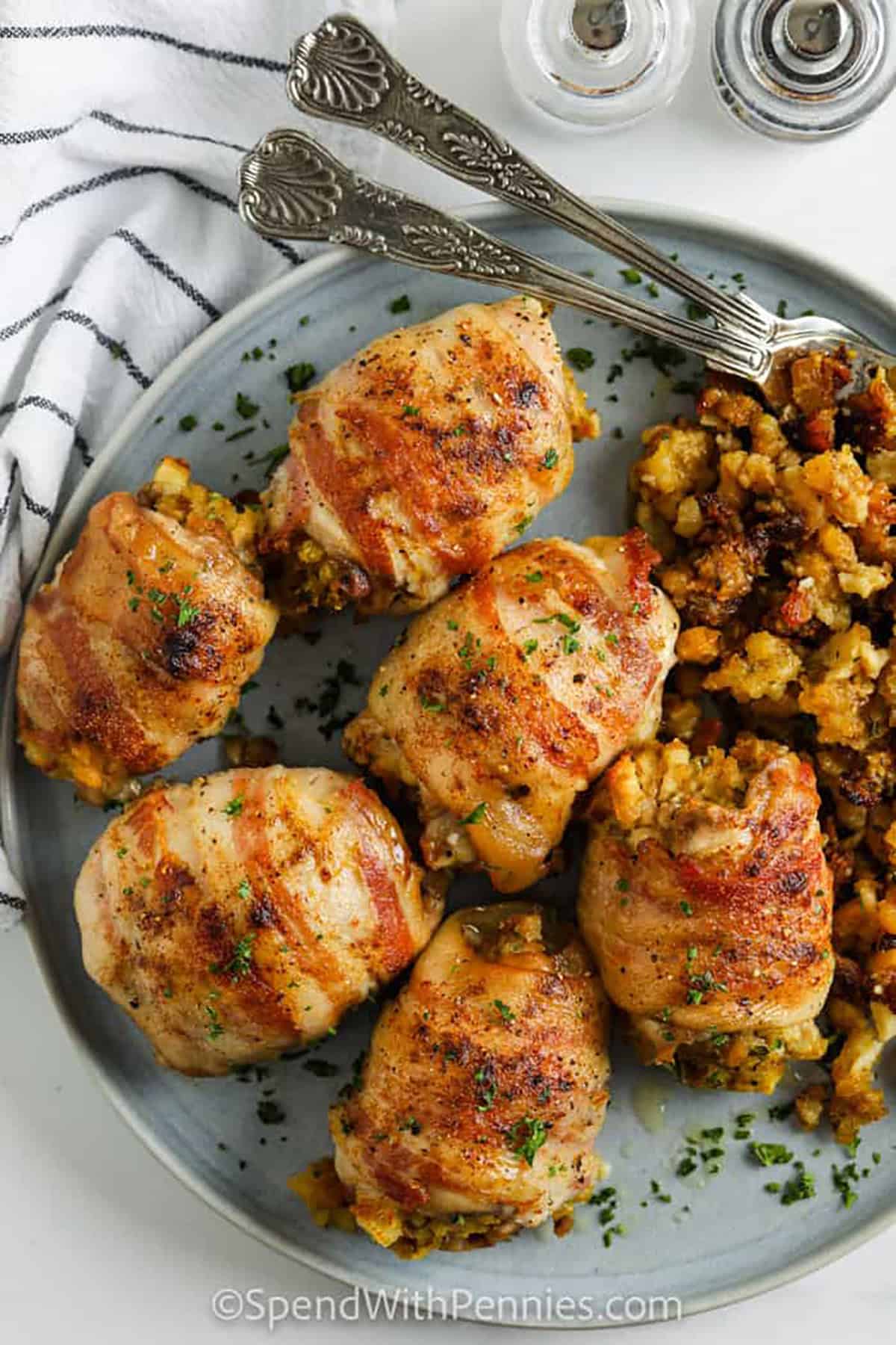 These bacon wrapped stuffed chicken thighs are full of savory flavor and baked in one dish for easy cleanup. The stuffing stays soft and seasoned in the center while the bacon helps the chicken stay tender and adds a crisp, smoky finish. This is a great recipe for Sunday dinner, holiday leftovers, or any night when you want a homemade meal that looks impressive without adding complicated steps. #spendwithpennies plated Stuffed Chicken Thighs with stuffing