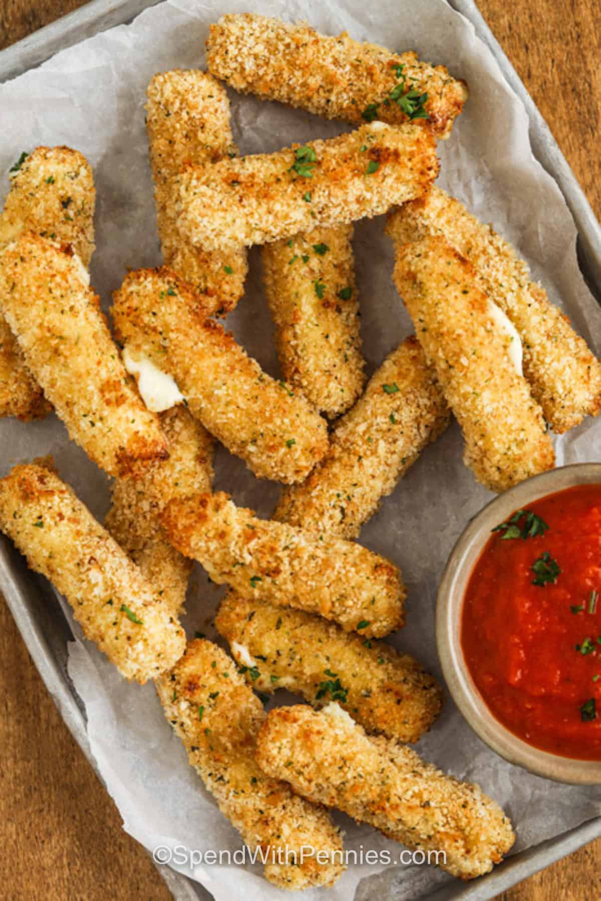 top view of baked Air Fryer Mozzarella Sticks on sheet pan with marinara