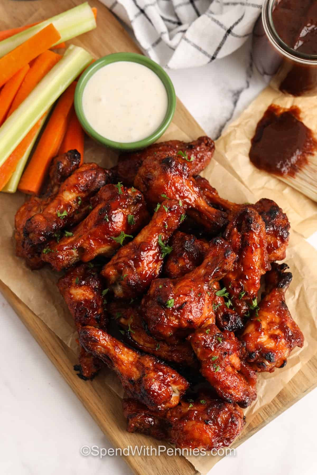 BBQ Chicken Wings on a wooden cutting board with veggies with dip