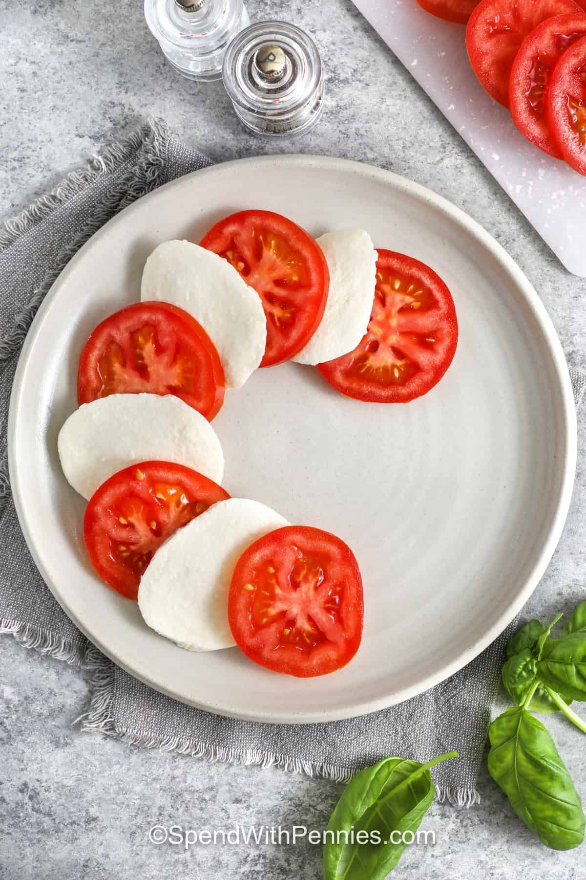 adding tomato slices and mozzarella slices to plate to make Caprese Salad