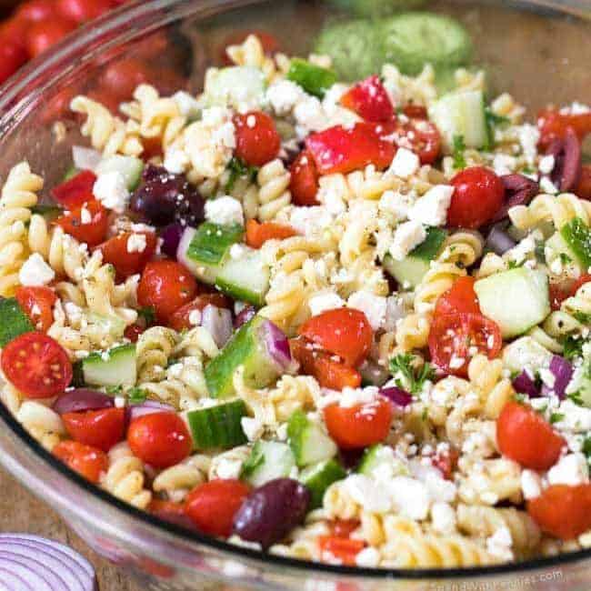 Greek Pasta Salad in a clear bowl with writing
