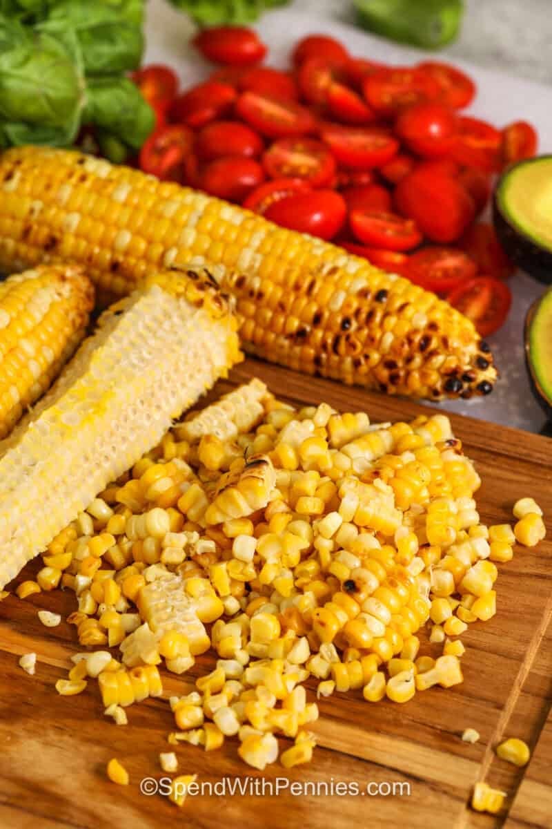 cutting corn off the cob to make Grilled Corn Salad