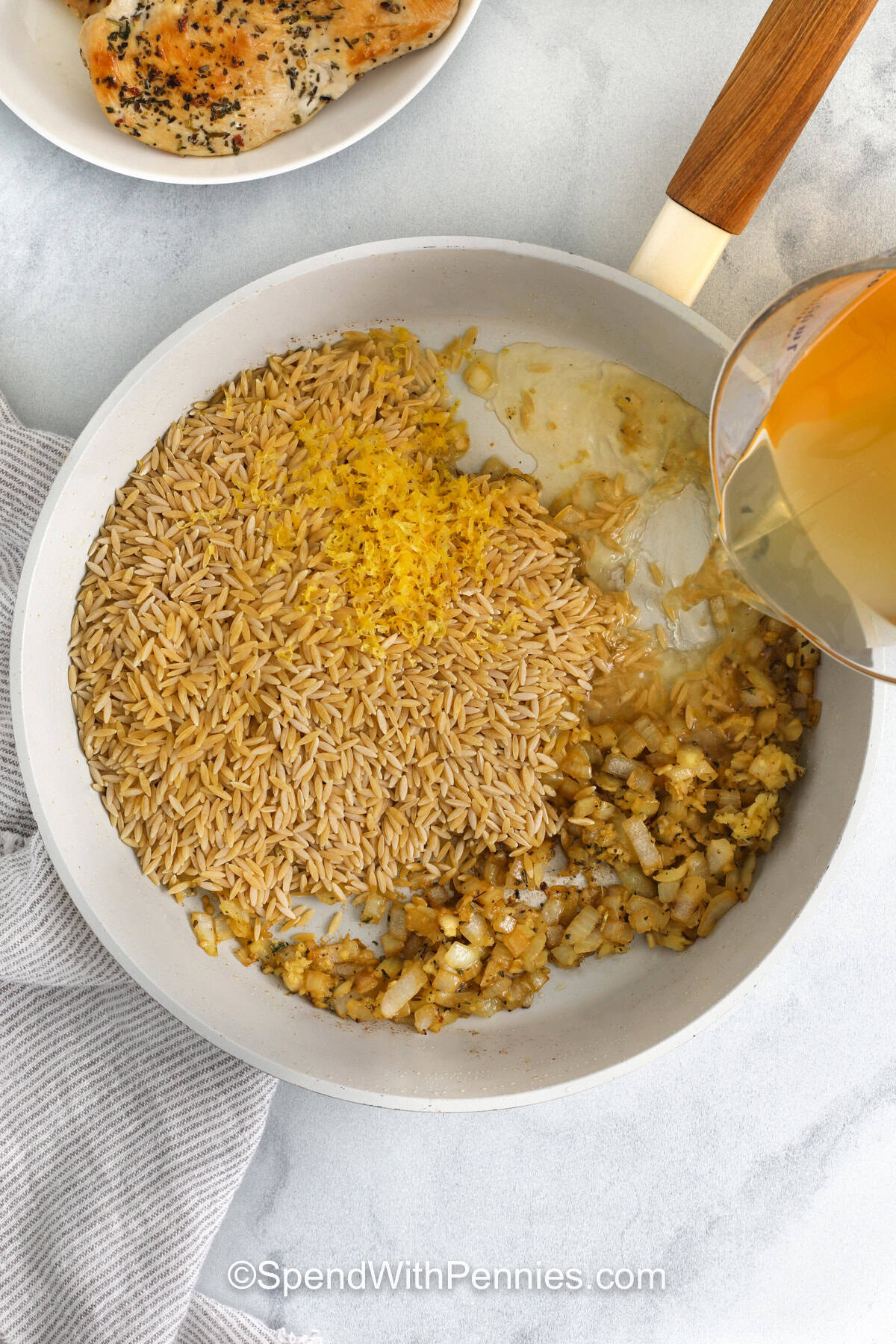 pouring broth over ingredients to make Lemon Chicken Orzo