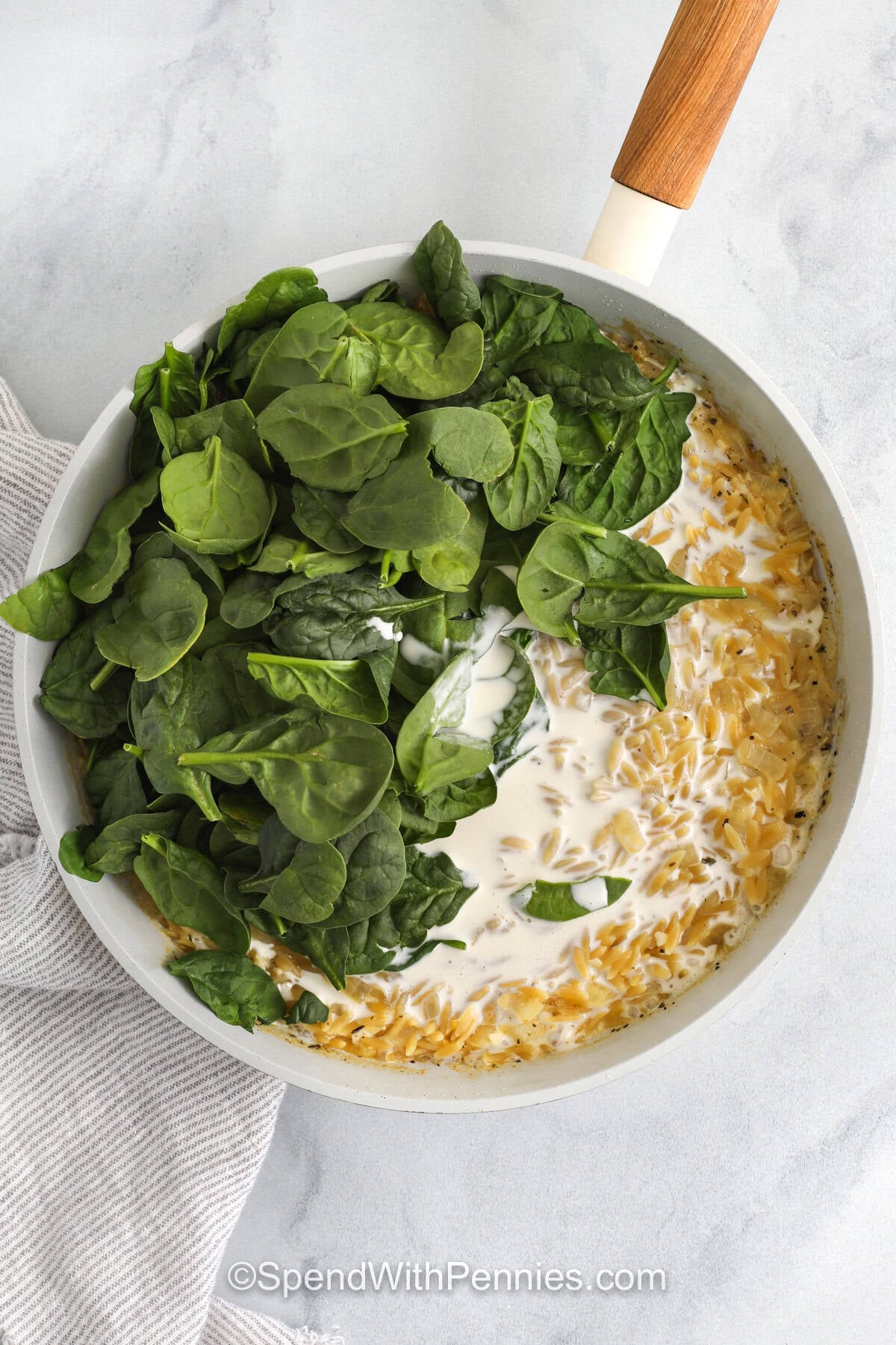 adding spinach and cream to ingredients to make Lemon Chicken Orzo
