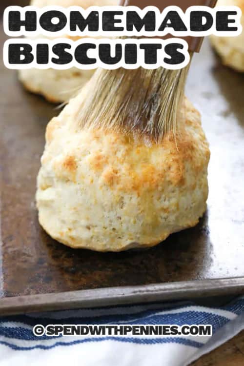 Fluffy homemade biscuits make any meal feel cozy, and this easy recipe uses ingredients you probably already have. Flour, butter, baking powder, baking soda, and milk come together quickly for biscuits that are golden on top and tender inside. Make them for brunch, serve them with dinner, or freeze extras for a quick homemade side later in the week. #spendwithpennies brushing butter over Homemade Biscuits on a sheet pan with a title