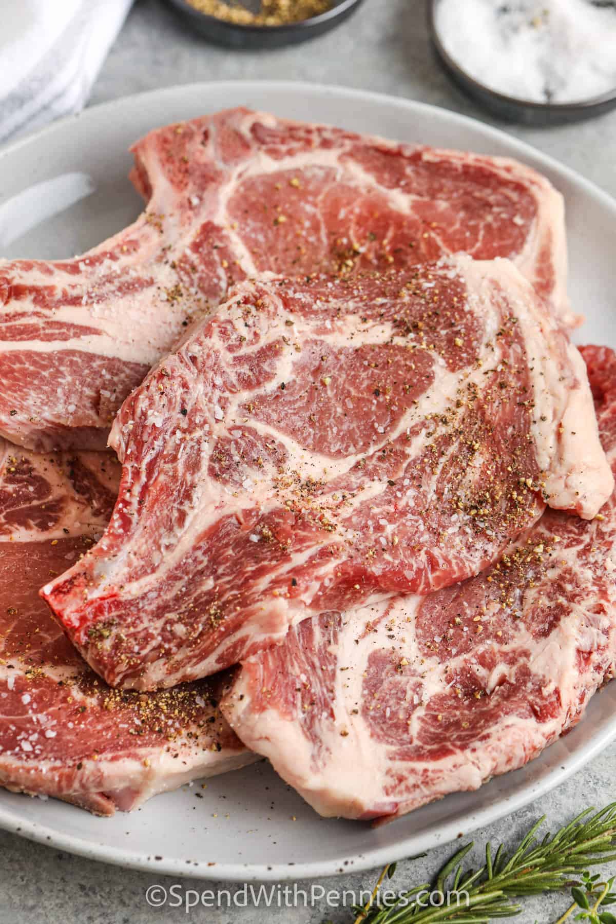 This easy recipe for pan seared pork chops keeps dinner simple and full of flavor. The chops are cooked in a skillet until golden, then topped with melted herb butter made with rosemary and thyme. A quick rest helps keep the pork tender, while a meat thermometer makes it easy to avoid overcooking. Serve these pork chops for weeknights, small dinners, or a cozy meal for two. #spendwithpennies adding seasonings to pork chops to make Pan Seared Pork Chops