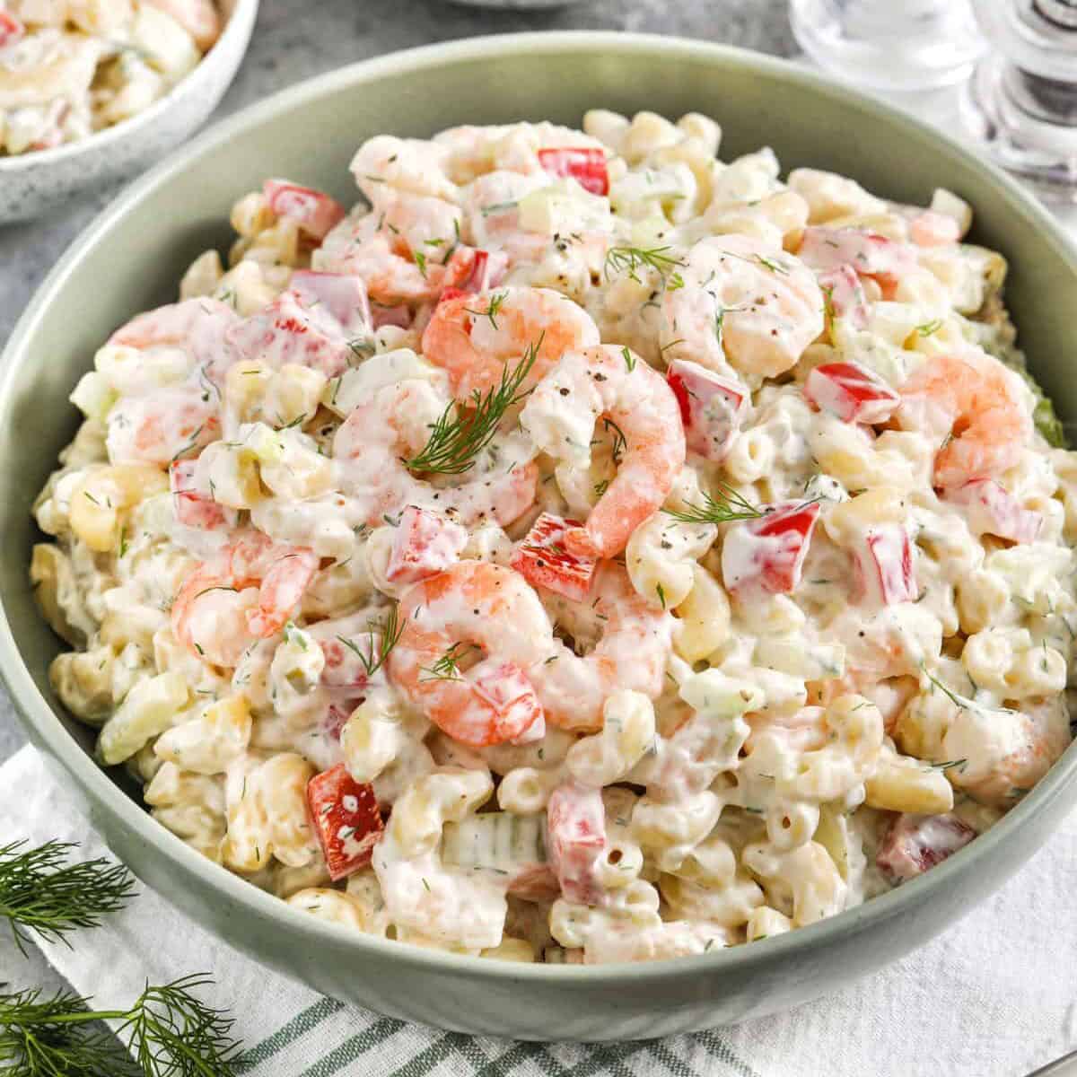 shrimp pasta salad in a green bowl with salt and pepper