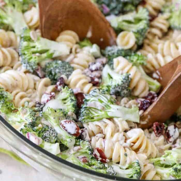Broccoli Pasta Salad being stirred with two wooden spoons