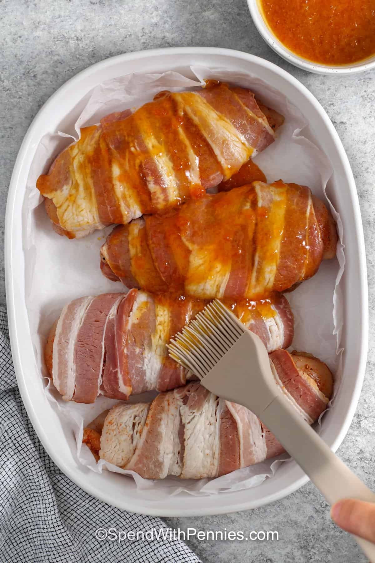 brushing apricot jam over Bacon Wrapped Chicken before cooking