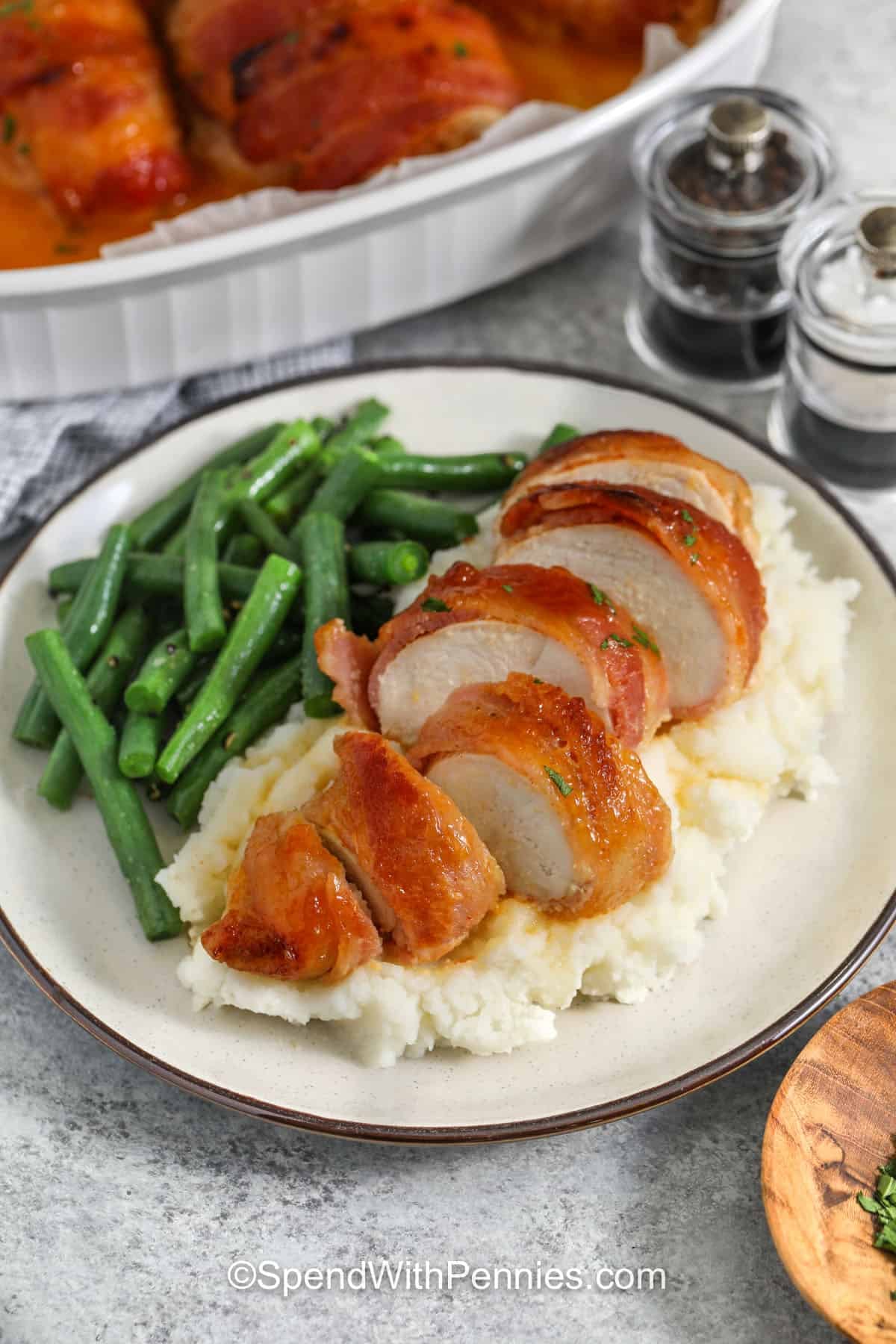 plated Bacon Wrapped Chicken with dish full in the back