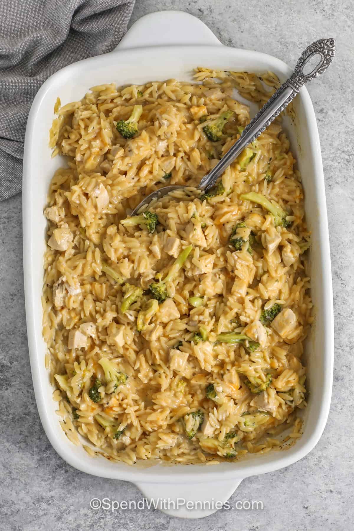 Make this chicken orzo bake when you need an easy and comforting dinner with simple ingredients. Cooked chicken, bite sized broccoli, dry orzo, chicken broth, milk, and cheddar cheese bake together until creamy and tender. This recipe is especially helpful for using leftover chicken or rotisserie chicken, and frozen broccoli can be added straight from the freezer for faster prep. #spendwithpennies Chicken Orzo Bake in the dish