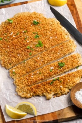 Sliced giant chicken cutlet on a cutting board with parsley