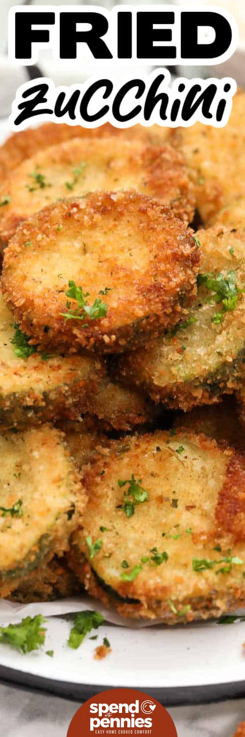 Crispy fried zucchini is an easy way to use fresh garden zucchini when you want something savory and snackable. Parmesan cheese and seasoned breadcrumbs create a flavorful crust, while quick pan-frying gives each slice a golden crunch. This fried zucchini recipe is great for dipping and pairs well with pasta, grilled chicken, burgers, or a casual appetizer spread. Pin this recipe for your next gathering. #spendwithpennies close up of Fried Zucchini Recipe on a plate with writing