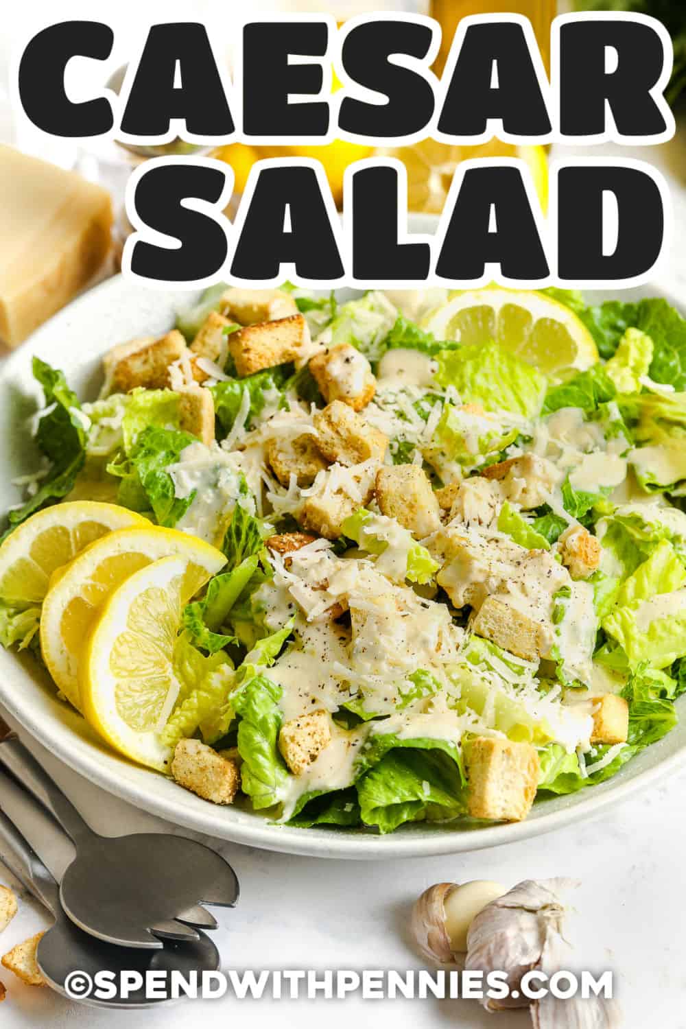 Classic Caesar salad is all about the contrast of crisp romaine, creamy dressing, crunchy croutons, and plenty of Parmesan cheese. This version uses fresh garlic, lemon juice, Worcestershire sauce, Dijon mustard, anchovy, and capers for bold flavor in every bite. Make the dressing ahead and toss the salad just before serving to keep the lettuce fresh and the croutons crunchy. #spendwithpennies bowl of Caesar Salad with a title