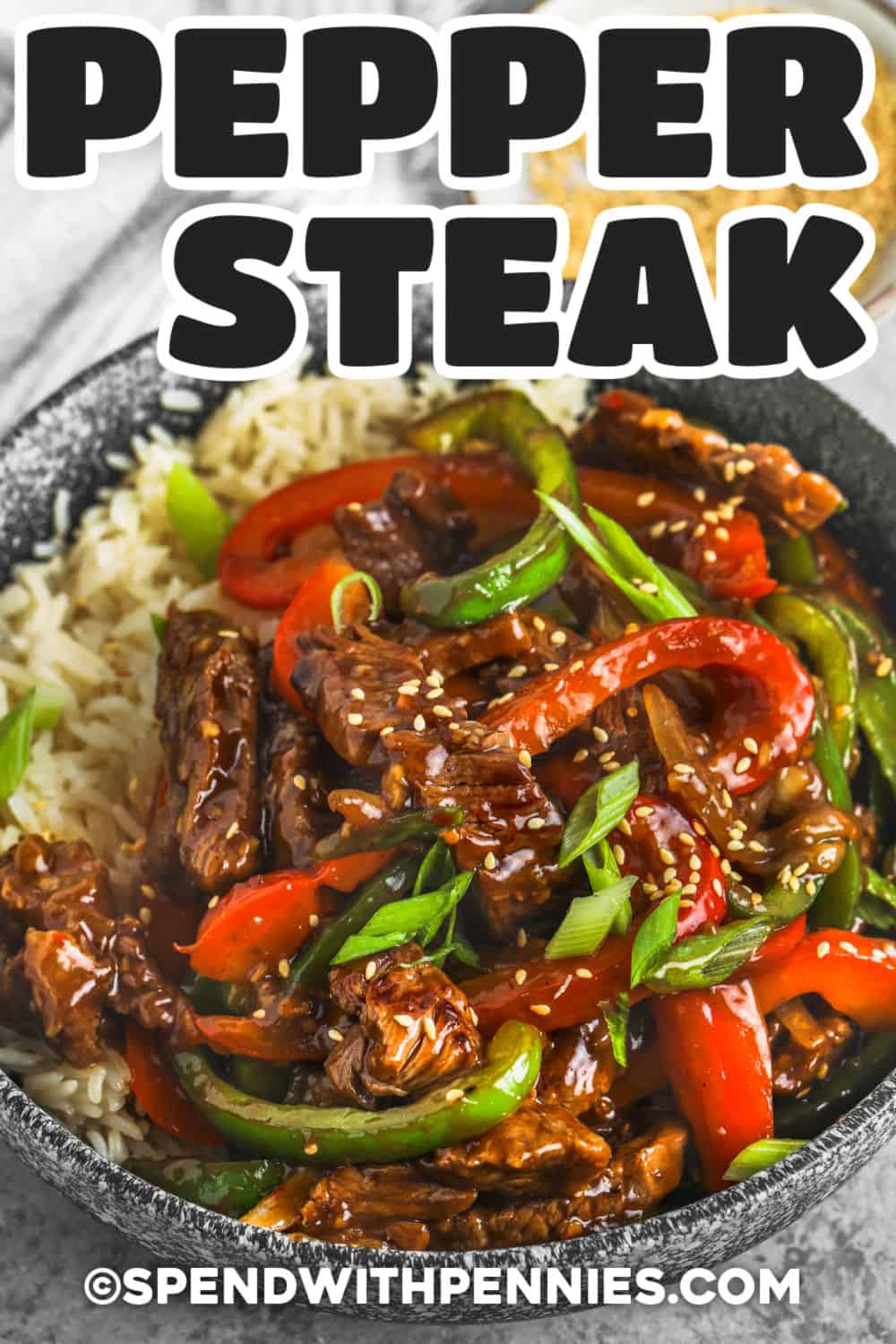 This pepper steak stir fry is packed with tender beef strips, crisp-tender peppers, and a rich garlic ginger sauce. A short marinade helps tonight's round beef become more flavorful, while a hot skillet gives the steak a good sear. Spoon this saucy beef pepper steak over steamed rice for a hearty family dinner with big takeout-style flavor. Pin this recipe for tonight's dinner. #spendwithpennies Pepper Steak stir fry in a bowl with a title
