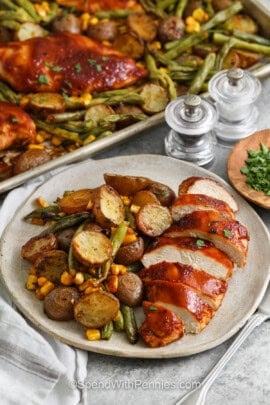 plated Sheet Pan BBQ Chicken with sheet pan full in the back
