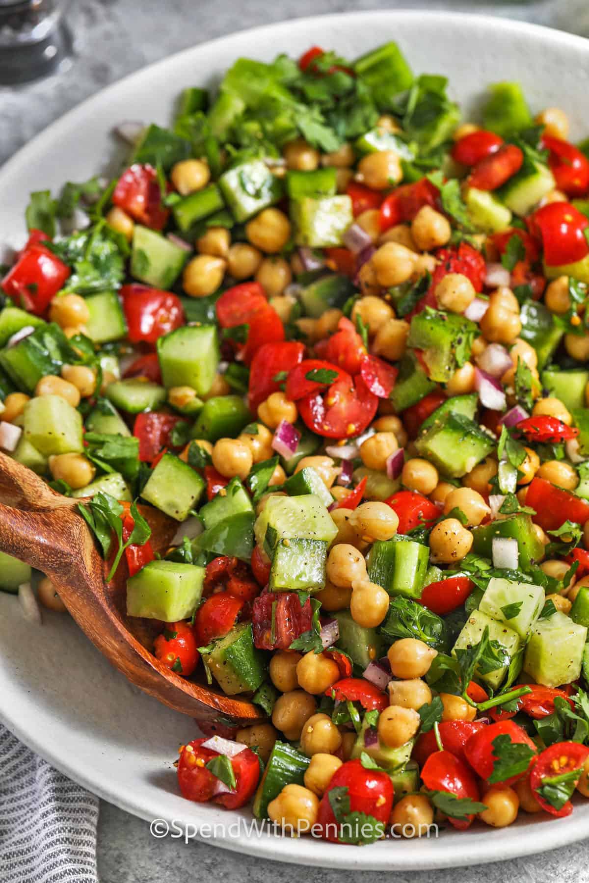 This vegan chickpea salad is fresh, filling, and easy to prepare without turning on the oven. Canned chickpeas are tossed with cucumber, grape tomatoes, crisp bell pepper, parsley, red onion, and a tangy cumin vinaigrette. A short chill gives the beans time to absorb the lemony dressing. Pack it for meal prep, serve it with pita and hummus, or add it to a platter of grilled vegetables. #spendwithpennies Chickpea Salad in a bowl