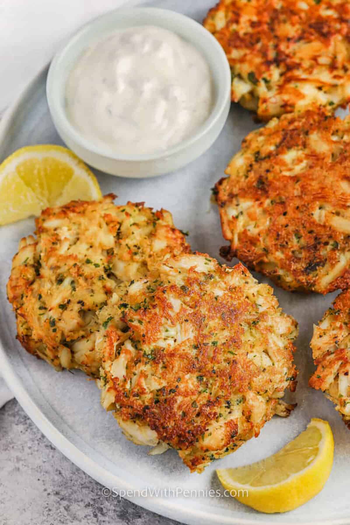 This easy crab cake recipe makes a restaurant-style seafood dinner possible without a complicated ingredient list. Lump crab meat is folded gently with panko, mayonnaise, egg, Dijon mustard, Worcestershire sauce, Old Bay, parsley, and lemon zest. Chilling helps the cakes hold together, and a quick skillet sear creates crisp edges. This crab cake recipe can be served as a main dish, tucked into sandwiches, or shaped smaller for party appetizers. #spendwithpennies plated Crab Cake Recipe with dip