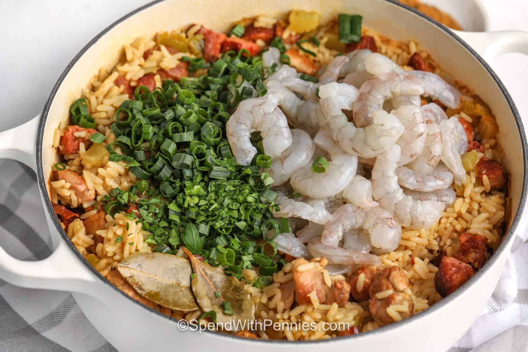 This one pot Cajun Jambalaya is smoky, savory, and full of Cajun flavor from browned sausage, chicken thighs, shrimp, broth, and vegetables. The oven method makes it easier to cook the rice without standing over the stove. Add green onions and parsley at the end for a fresh finish, then serve with bread or a crisp salad. Save this recipe for dinner tonight. #spendwithpennies close up of Cajun Jambalaya