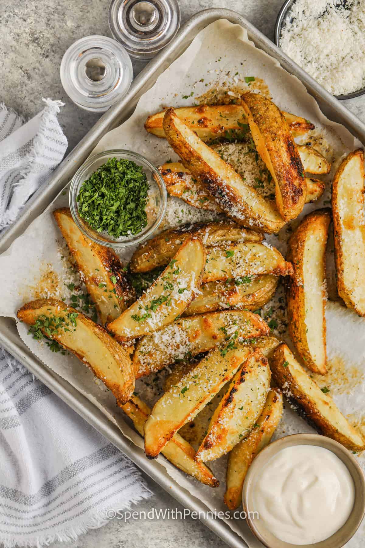 sheet pan of Crispy Baked Potato Wedges with bowl of dip