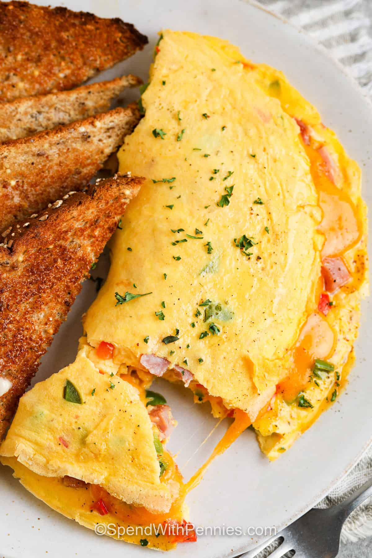 This easy Denver omelet brings together fluffy eggs, diced ham, tender bell peppers, and melted cheese in a warm, comforting breakfast. Use pre-diced ham and shredded cheddar to shorten the prep, or prepare the filling ahead for even faster cooking. The recipe works well with mushrooms, bacon, sausage, or another melting cheese when substitutions are needed. Add this omelet recipe to your breakfast collection today. #spendwithpennies Denver Omelet with toast