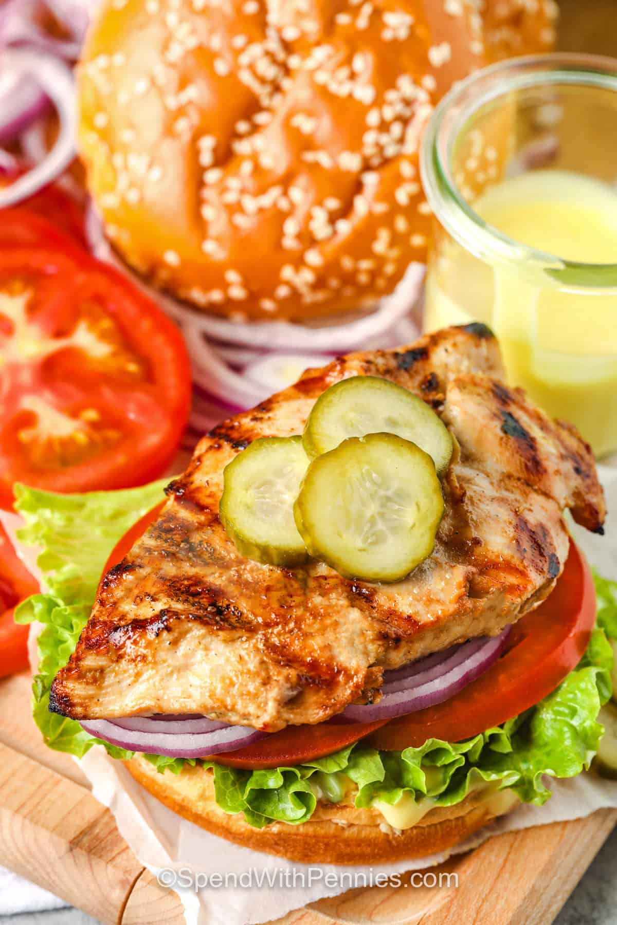 A grilled chicken sandwich is a fresh and satisfying alternative to the usual backyard burger. This version starts with a simple Dijon marinade that gives the chicken plenty of tangy flavor without a long list of ingredients. Pounding each breast to an even thickness keeps cooking quick and helps prevent dry spots. Serve the juicy chicken on toasted buns with honey mustard and crisp vegetables for a family-friendly summer dinner. #spendwithpennies Grilled Chicken Sandwich with pickles
