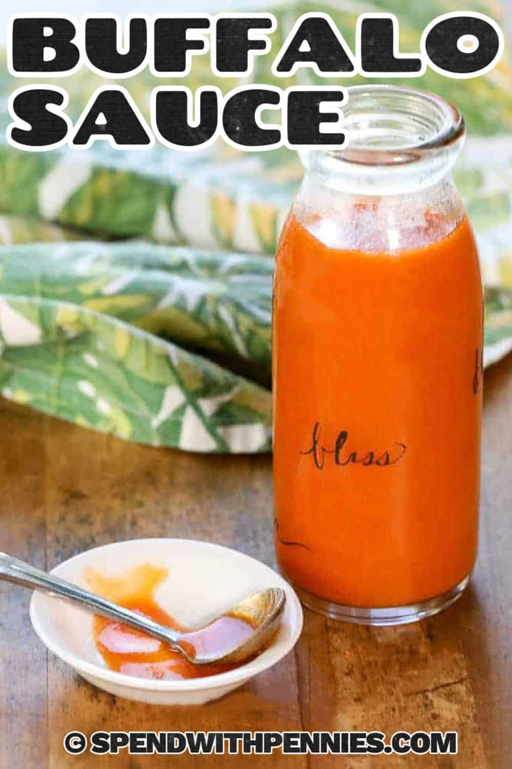 Make homemade Buffalo sauce in five minutes with hot sauce, butter, and a dash of garlic powder. The result is a silky, spicy sauce that clings to baked or air-fried chicken wings without covering up their crisp texture. Use it as a drizzle for tacos and pizza, mix it into shredded chicken, or combine it with sour cream for a quick dip. Pin this simple Buffalo sauce recipe when you need an easy game-day favorite. #spendwithpennies Buffalo Sauce in a jar and on a spoon with a title