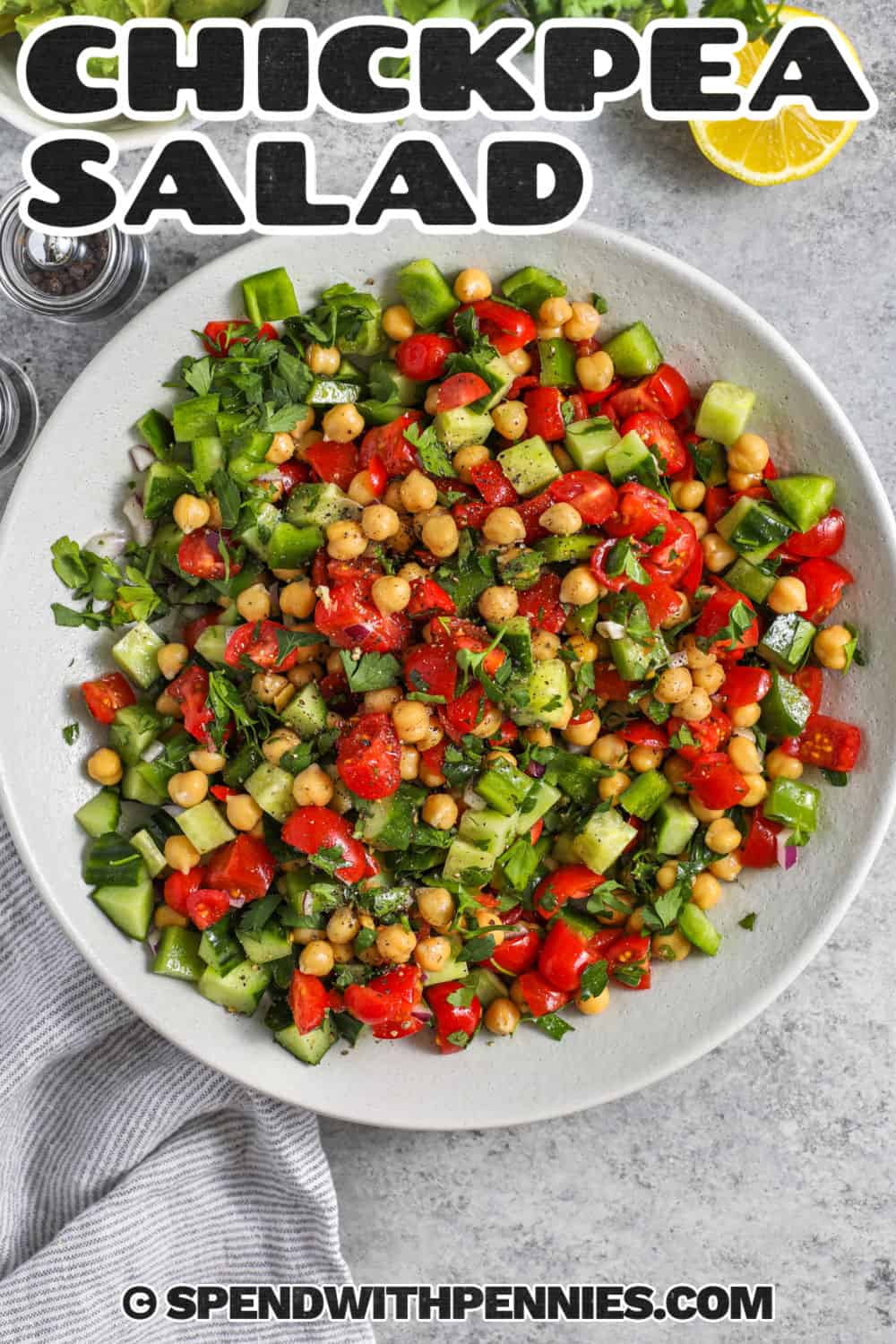 Mediterranean chickpea salad is a fresh and satisfying way to turn canned chickpeas into an easy lunch or side dish. Crisp cucumber, tomatoes, green bell pepper, parsley, and red onion add color and crunch, while a lemony red wine vinaigrette keeps every bite bright. Add creamy avocado before serving, or leave it out for a salad that stays crisp during several days of meal prep. Pin this recipe to your sides board. #spendwithpennies top view of Chickpea Salad in a bowl with a title