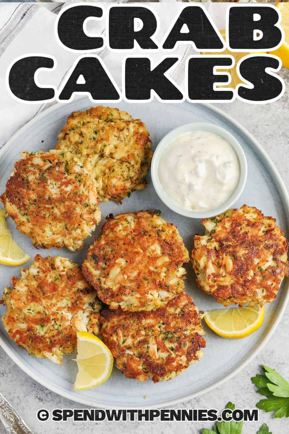 This homemade crab cake recipe is easier to prepare than it looks, especially when the mixture is made and shaped ahead. These lump crab cakes combine sweet crab meat with mayonnaise, egg, Dijon, Old Bay, lemon zest, and light panko breadcrumbs. After chilling, they cook in a skillet until browned outside and tender inside. Pin it to your seafood board. #spendwithpennies Crab Cake Recipe with dip and lemon slices with a title