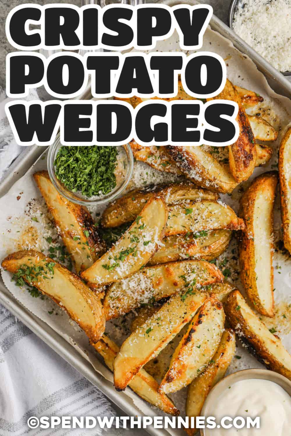 These crispy baked potato wedges have the golden edges, fluffy centers, and savory flavor everyone looks for in a potato side. The wedges are seasoned with Parmesan cheese, garlic powder, onion powder, and seasoned salt before roasting in the oven. Serve them with ketchup, ranch, aioli, chicken, steak, or burgers for an easy meal. Pin this crispy baked potato wedges recipe for your next weeknight dinner. #spendwithpennies Crispy Baked Potato Wedges with parmesan and parsley and a title