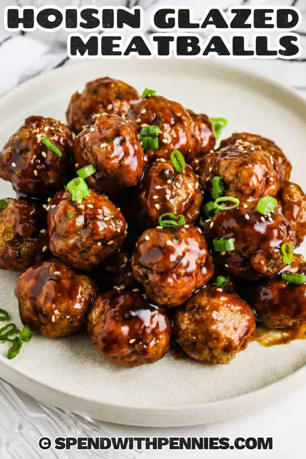 Hoisin meatballs are a simple way to make a flavorful appetizer or weeknight dinner with ground pork, panko, fresh ginger, green onions, and toasted sesame oil. The meatballs bake until juicy, then get coated in a glossy hoisin sauce that tastes sweet, savory, and just spicy enough without being complicated. Pin it to your dinner board. #spendwithpennies hoisin meatballs on a white plate