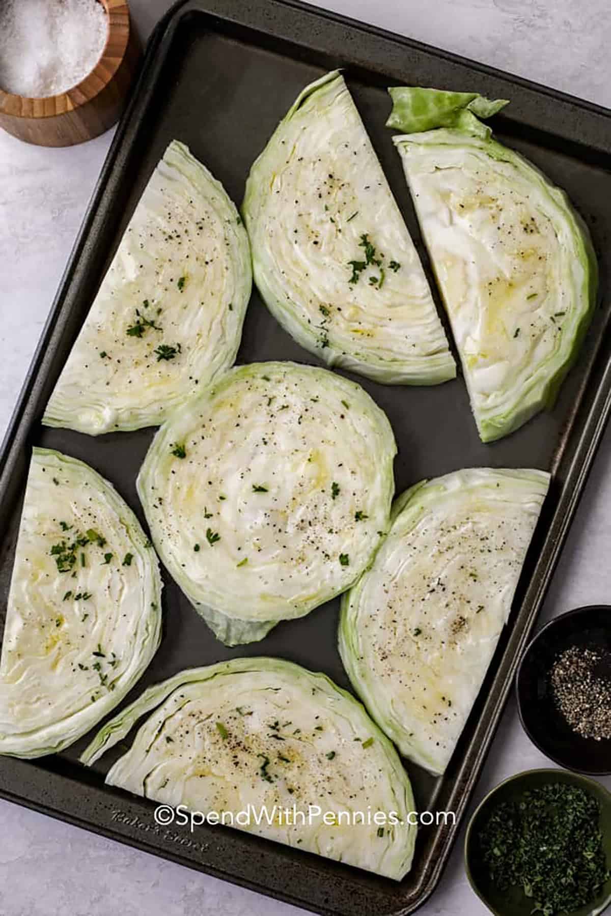 adding seasoned cabbage to the sheet pan to make Roasted Cabbage Steaks