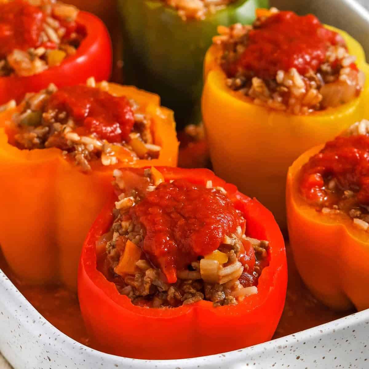 Classic stuffed peppers are a practical family dinner with simple ingredients and big flavor. Bell peppers are filled with ground beef, Italian sausage, long grain rice, diced tomatoes, and marinara sauce, then baked until the peppers are tender. This recipe is great for meal prep because leftovers reheat well and the peppers can be assembled ahead for the freezer. Pin these stuffed peppers to your dinner board. #spendwithpennies Stuffed Peppers in a dish before cooking