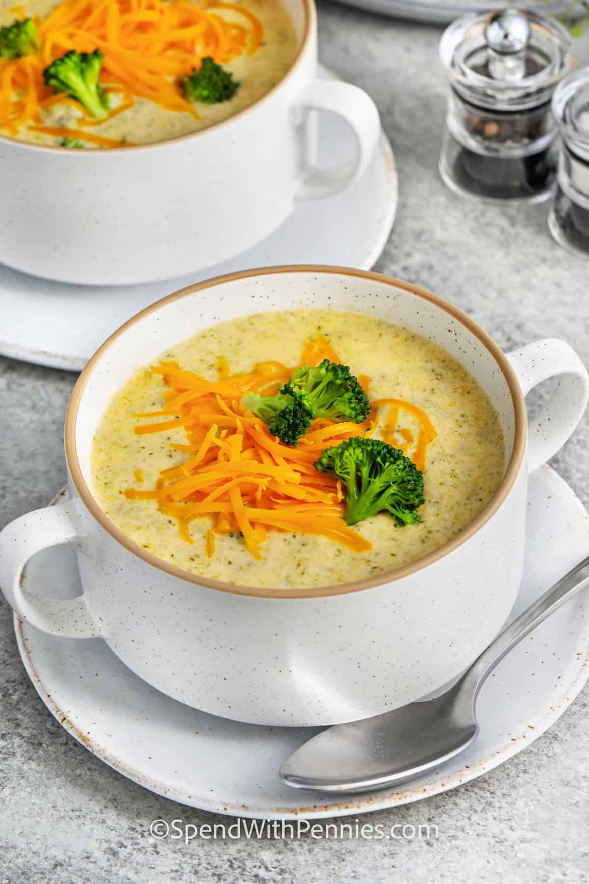 Broccoli cheddar soup gets an extra-creamy finish from a combination of sharp cheddar, Parmesan, and cream cheese. The broccoli is simmered until tender and partially blended, giving the soup a thick, velvety base with tender pieces throughout. Half and half adds richness while a little cornstarch helps everything stay spoonably creamy. Serve this homemade soup with warm bread or salad. Save this recipe for your comfort-food collection. #spendwithpennies bowls of Broccoli Cheddar Soup