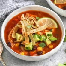 bowls of Chicken Tortilla Soup with lime and avocado on top.