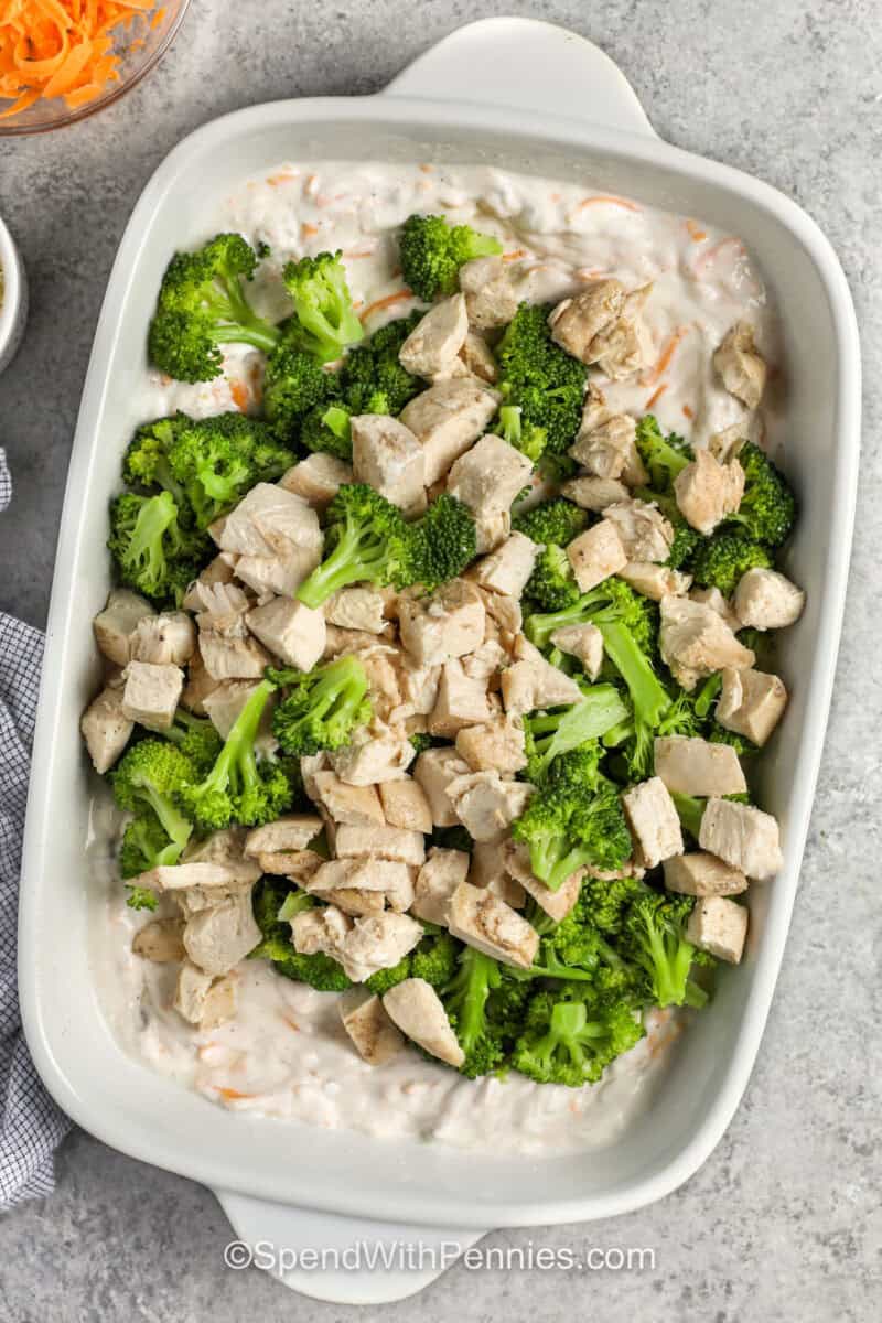 adding chicken and broccoli to ingredients in dish to make Chicken Divan.
