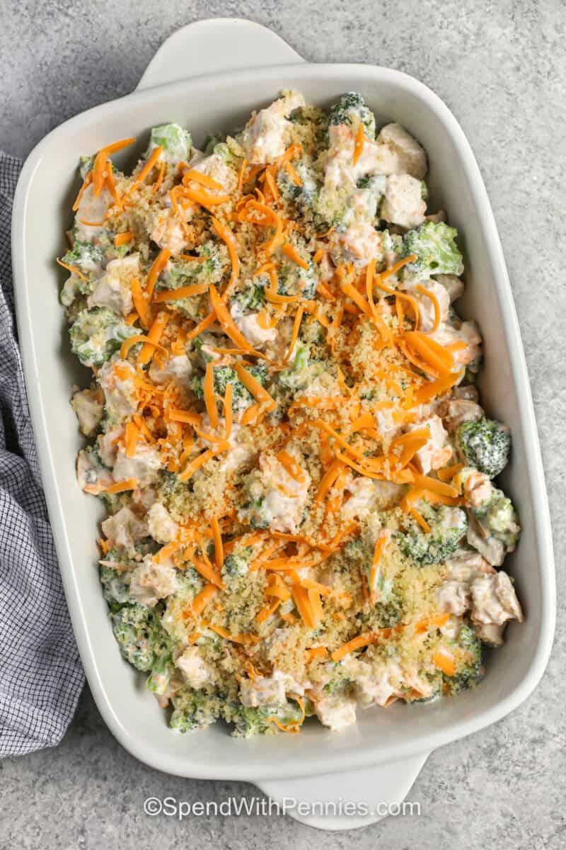 adding cheese and bread crumbs to dish to make Chicken Divan.