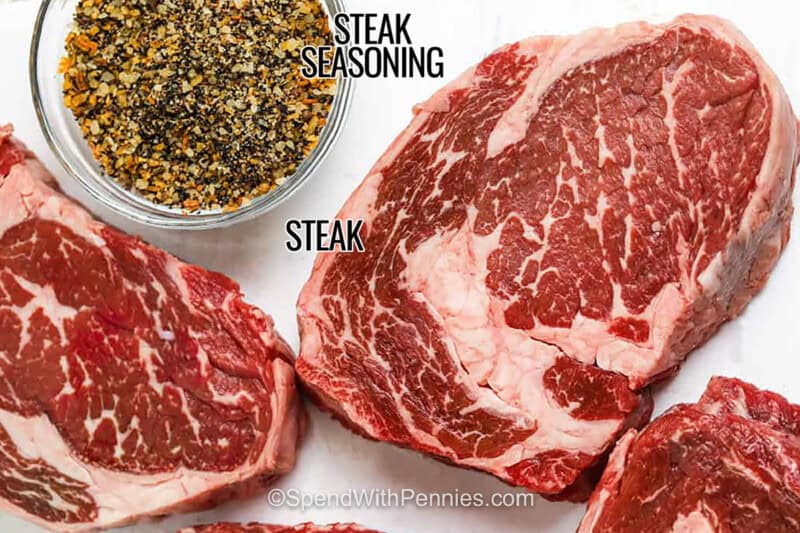 steak seasoning in a bowl with steaks and labels to make Perfect Ribeye Steak