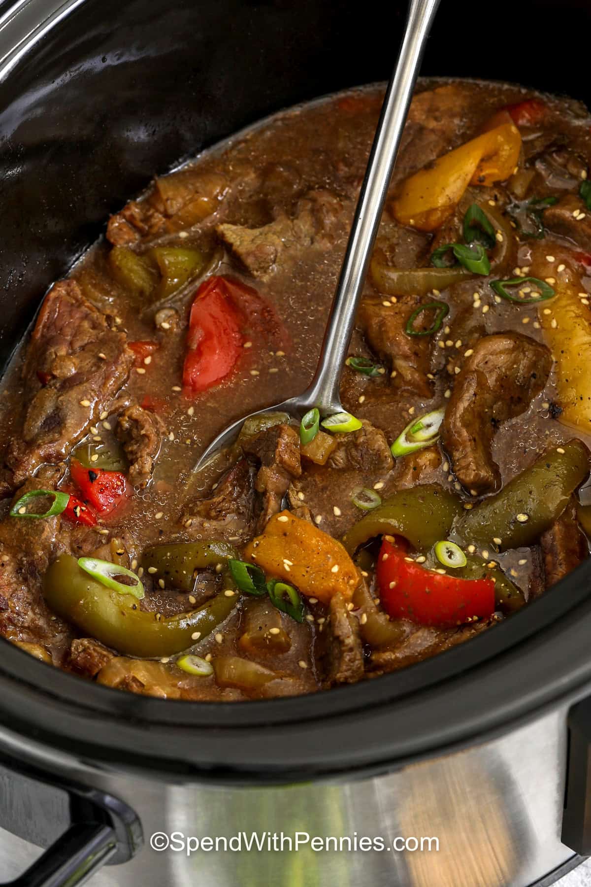 Bring slow cooker pepper steak to the table for a hearty meal loaded with tender beef, bell peppers, and onions. The sauce has a delicious mix of soy sauce, ginger, honey, garlic, and Worcestershire sauce, with red pepper flakes for a little kick. Spoon the flavorful mixture over rice or noodles for a satisfying dinner the whole family can enjoy. This easy slow cooker recipe is a great way to make dinner simple. Add it to your menu today. #spendwithpennies close up of Slow Cooker Pepper Steak in the cooker