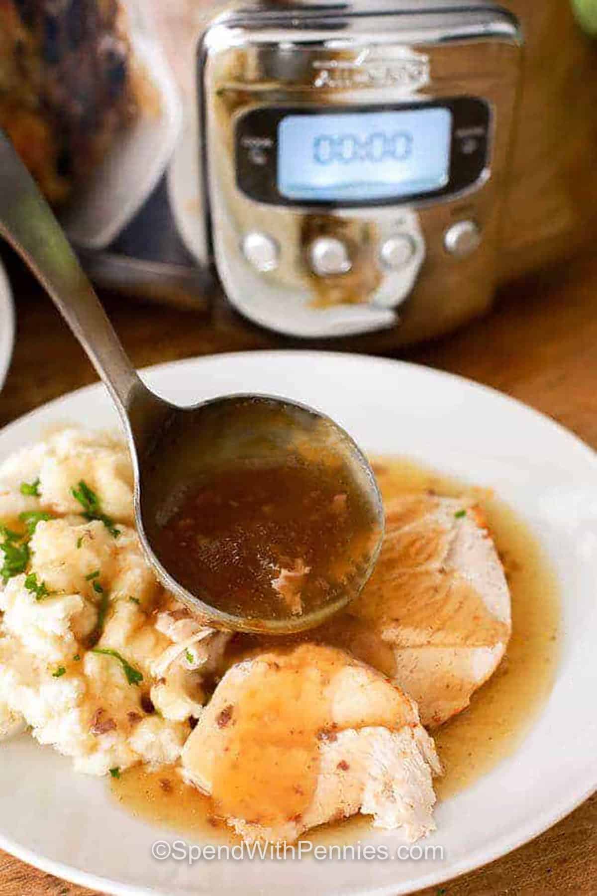 Make slow cooker whole chicken and gravy when you want the comfort of a traditional chicken dinner with much less hands-on work. The chicken cooks breast-side up with paprika, garlic, parsley, and thyme until juicy and easy to carve. After cooking, the seasoned drippings are whisked with a cornstarch slurry to make a savory gravy. Serve it with mashed potatoes and a green vegetable. Save this simple slow cooker recipe today. #spendwithpennies plated Slow Cooker Whole Chicken & Gravy with cooker in the background