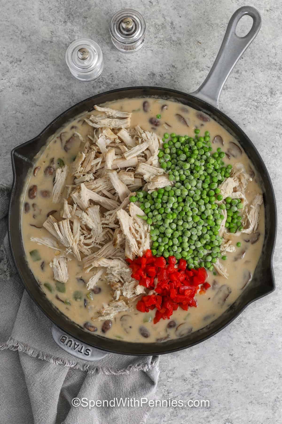 Turkey à la king brings leftover turkey to the table in a delicious new way. This easy skillet dinner combines tender turkey with mushrooms, peas, bell pepper, and pimentos in a creamy homemade sauce. Spoon it over rice, pasta, or biscuits for a filling meal that makes simple ingredients shine. It is a great way to use cooked turkey without serving the same leftovers again. Save this recipe and make it soon. #spendwithpennies adding turkey pimentos and peas to pan to make Turkey A La King